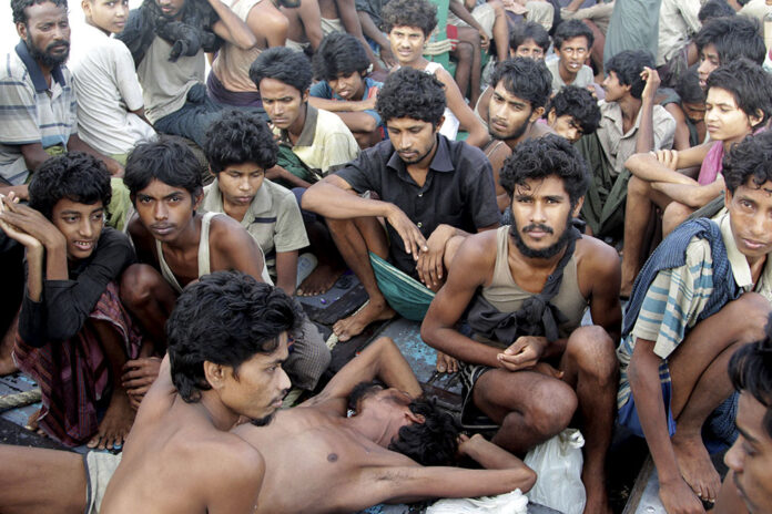 Migrants including Myanmar Rohingya Muslims sit on the deck of their boat as they wait to be rescued by Acehnese fishermen on May 20, 2015, on the sea off East Aceh, Indonesia. Photo: S. Yulinnas / Associated Press