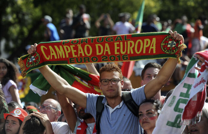 A fan holds a scarf that says 'Portugal European Champion Euro 2016' while waiting for the arrival of Portugal's national soccer team July 11 in Lisbon, Portugal. Photo: Paulo Duarte / Associated Press