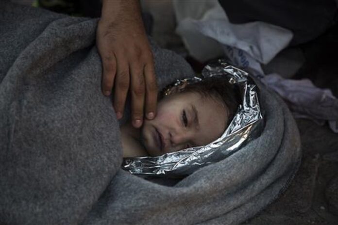 In this Oct. 28, 2015 file photo, paramedics and doctors care for a baby girl after a boat with refugees and migrants sunk while was crossing the Aegean sea from Turkey to the Greek island of Lesbos. Photo: Associated Press