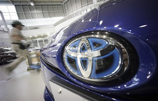A worker walks past a Toyota car at a Toyota showroom in Tokyo, Wednesday, June 29, 2016. Photo: Eugene Hoshiko / Associated Press