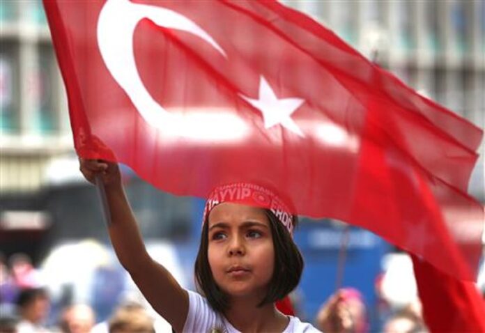 A Turkish girl wearing a headband bearing the name of Turkish president Recep Tayyip Erdogan waves her nation flags during a pro-government demonstration in front of the old parliament building, in Ankara, Turkey, Wednesday, July 20, 2016. Photo: Hussein Malla