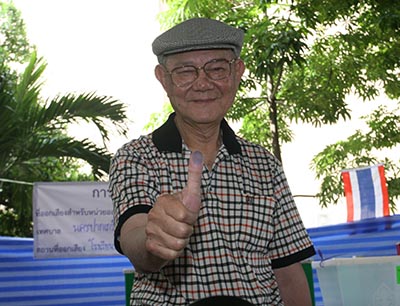 Constitution drafting committee chairman Meechai Ruchuphan shows his thumb to reporters after casting his vote Sunday in Bangkok.