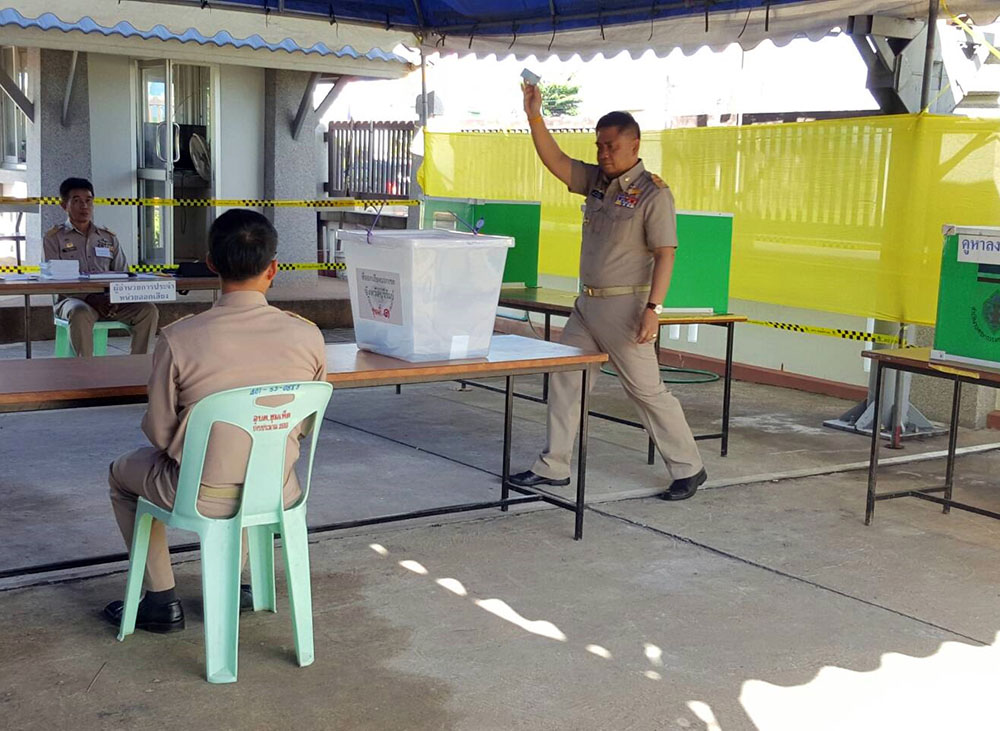 A local official in Buriram raises his ballot before depositing it in a ballot box Sunday.