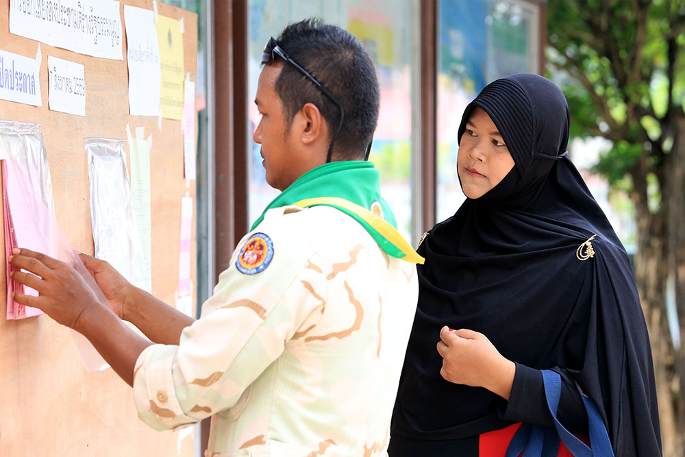  A paramilitary ranger and civilian woman check the rolls at a polling station Sunday in Yala province.