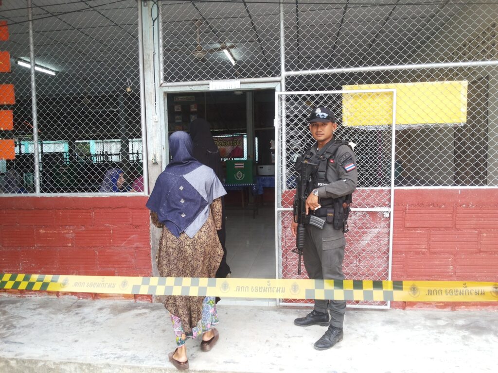 A security officer guards a polling station as a woman enters to vote Sunday in Pattani province.