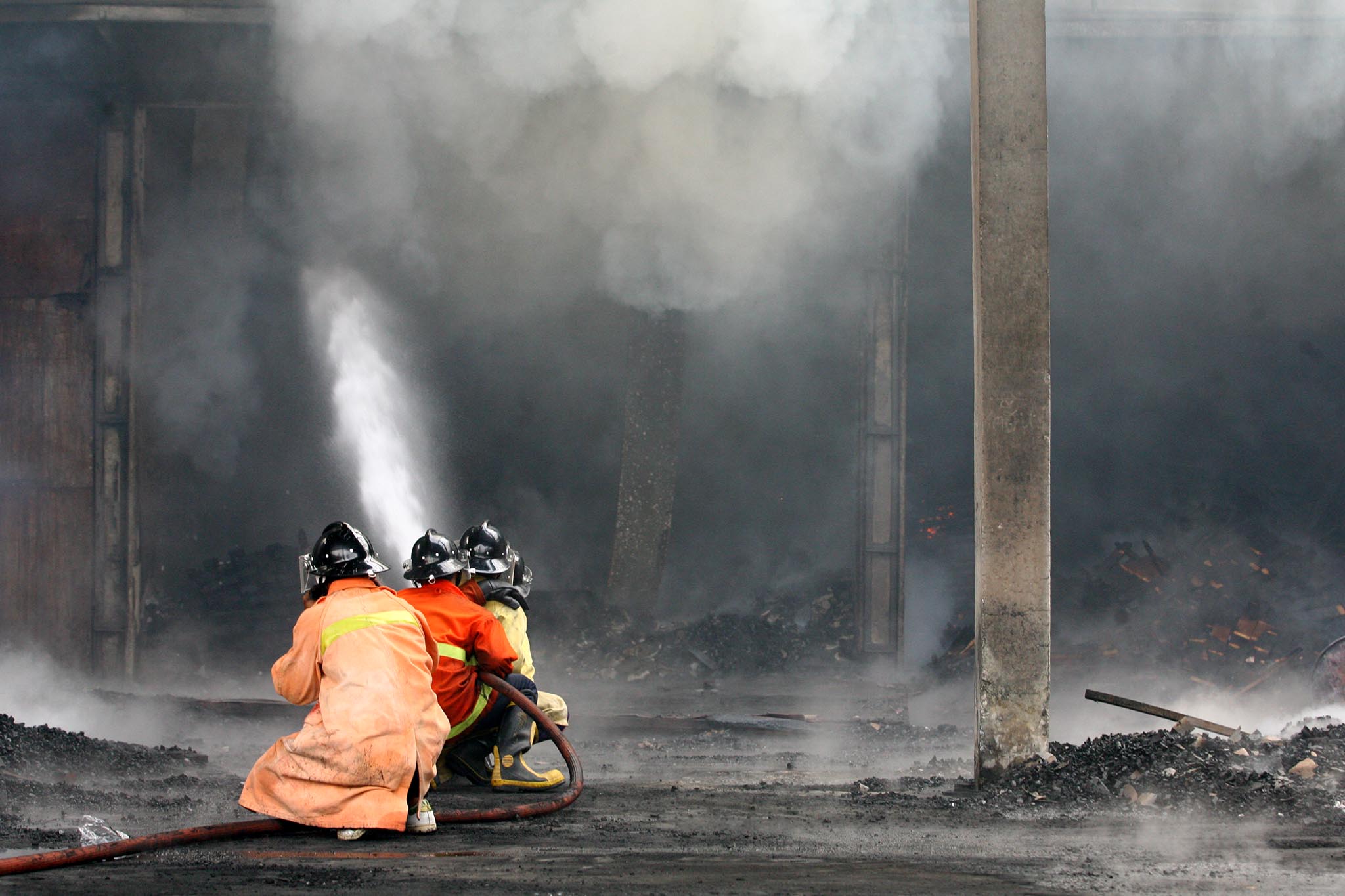 Firefighters work to extinguish a blaze Monday at the remnants of a rubber processing plant in Yala province.