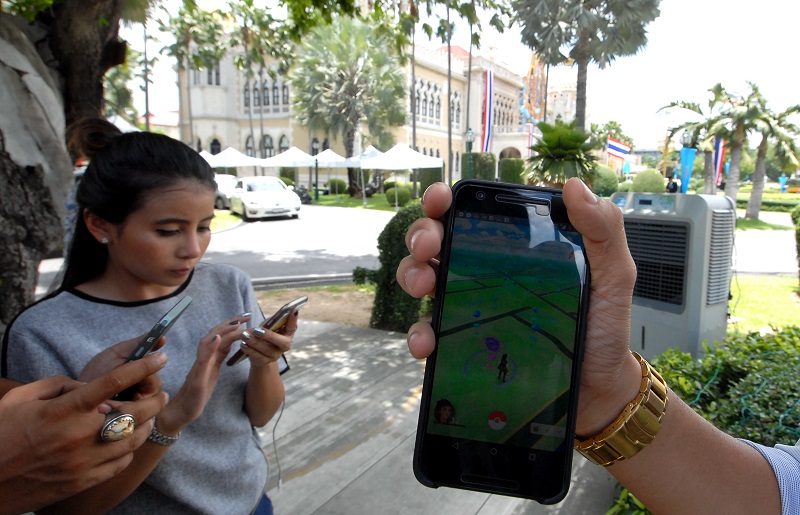 Members of the press corps hunt for some Pokemon on Monday in front of the Government House.