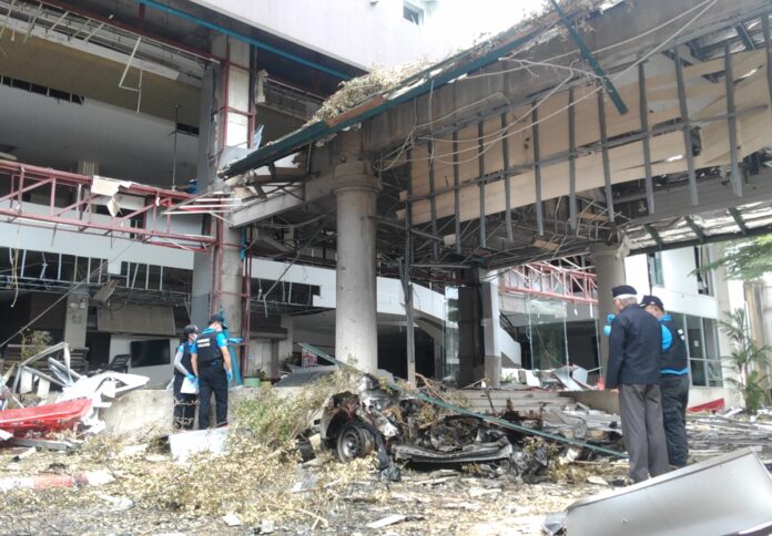 Police officers on Wedneday morning inspect the site of the deadly twin car bomb that struck a hotel in Pattani province.