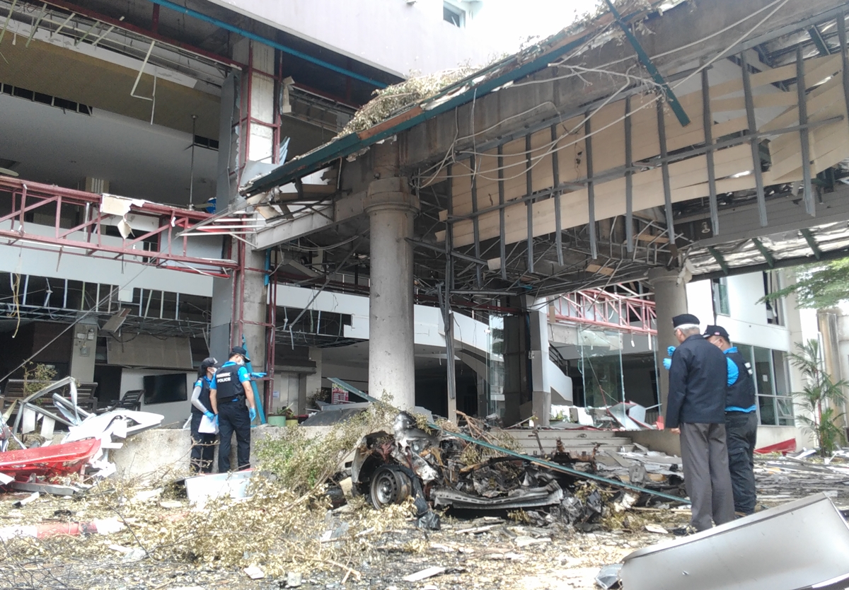 Police officers on Wedneday morning inspect the site of the deadly twin car bomb that struck a hotel in Pattani province.