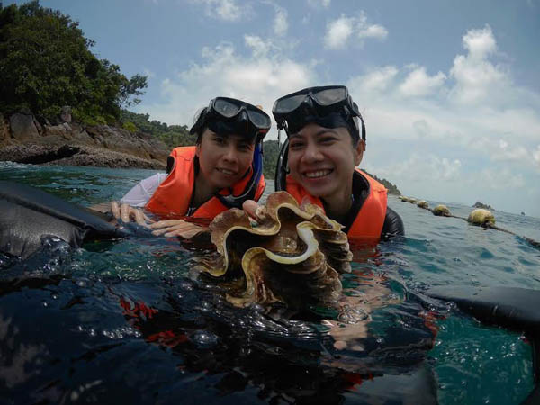 Unidentified tourists pose with a giant clam Tuesday in the sea off Koh Chang in an image circulated on social media.