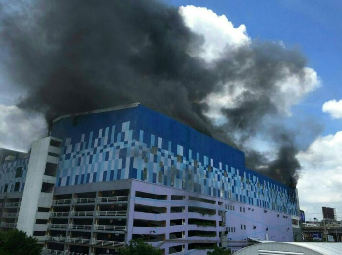 Smoke rises above Major Cineplex Pinklao prior to the theater’s roof collapsing as it was engulfed in flames Thursday in western Bangkok. Photo: Matichon