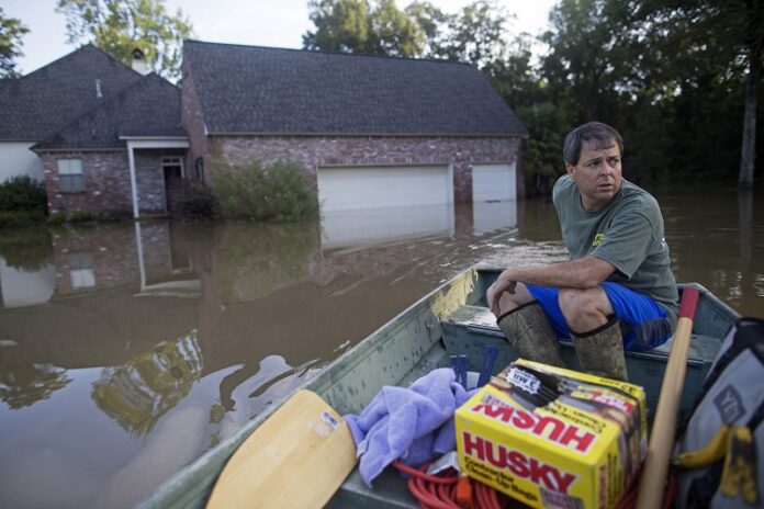 David Key boats away from his flooded home after reviewing the damage on Tuesday in Prairieville, Louisiana. The insurance adjuster fled his home as the flood water was rising with his wife and three children and returned today to assess the damage. Photo: Max Becherer / Associated Press