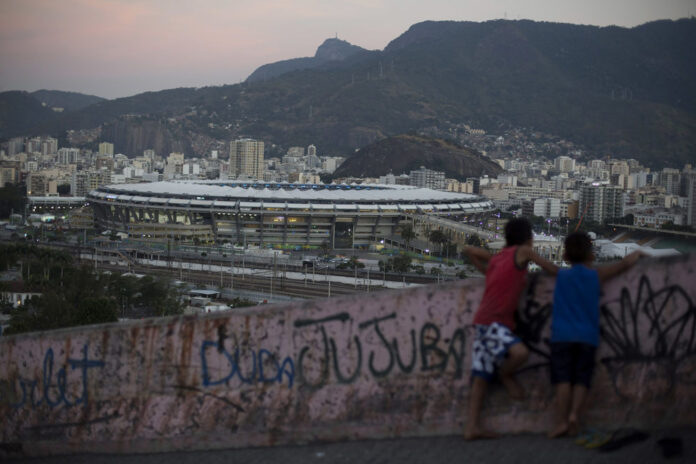 Two boys look out from the Mangueira slum toward the Maracana Stadium during the opening ceremonies of Rio's 2016 Summer Olympics. Photo:Leo Correa / Associated Press