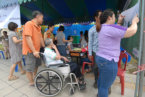 An eldery disabled voter is brought to a polling station in Nonthaburi province on Sunday.