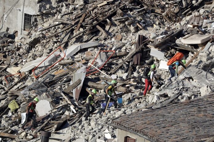 Rescuers make their way through destroyed houses following an earthquake on Thursday in Pescara Del Tronto, central Italy. Photo: Gregorio Borgia / Associated Press
