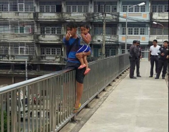 Peerawat Klomkliang gestures as he threatens to jump from a pedestrian overpass with his 3-year-old son on Friday west of Bangkok.