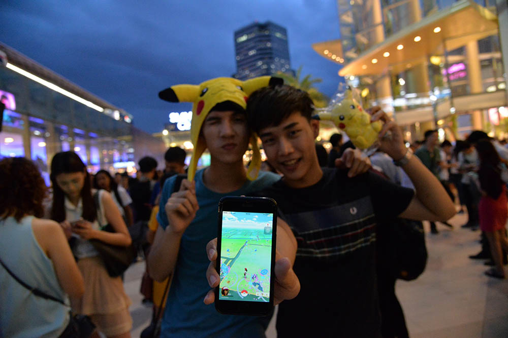 Two Pokemon Go players pose for a photo Tuesday evening at Bangkok's Siam Paragon shopping mall. The mall was choked with players wandering around playing the game late into the evening.