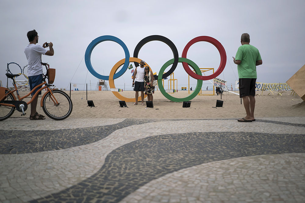 People take photos by the Olympic rings decorating Copabana Beach on Thursday in Rio de Janeiro, Brazil. Photo: Felipe Dana / Associated Press