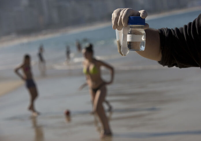 Doctoral candidate Rodrigo Staggemeier shows samples of water and sand from Copacabana Beach, collected for a study commissioned by The Associated Press, on July 11 in Rio de Janeiro, Brazil. Photo: Silvia Izquierdo / Associated Press
