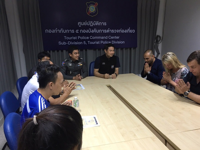 A group of tourists and their tour guide apologize for the dress worn by the woman, second from right, Wednesday at Phuket Tourist Police Command Center.