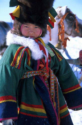 A Nenet nomad child with reindeer in background. Photo: Oyvind Ravna / Wikimedia Commons