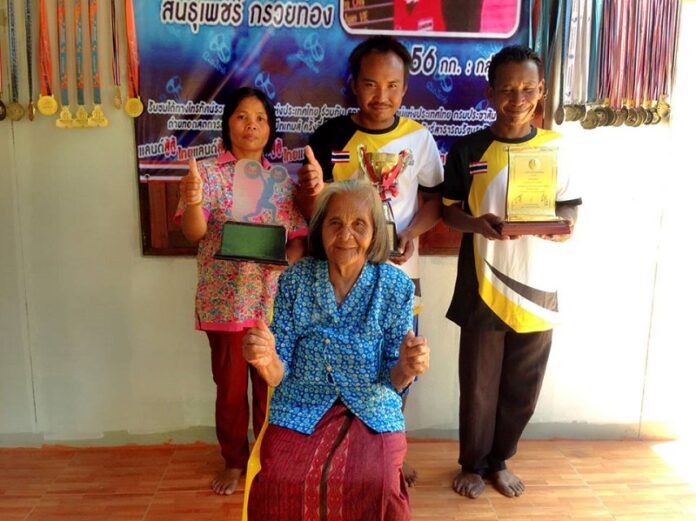 Sinphet Kruaithong’s 82-year-old grandmother Subin Kongthap poses to cheer for her grandson on Monday in Surin province. Photo: Matichon