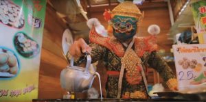Masked demons make coconut pudding in the music video “Tiew Thai Me Hey (Travel in Thailand is Fun)” 