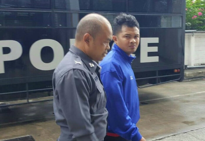 Panuwat Singhsahat, at right, is escorted by an officer at the Wang Thonglang police station in August. Photo: Matichon