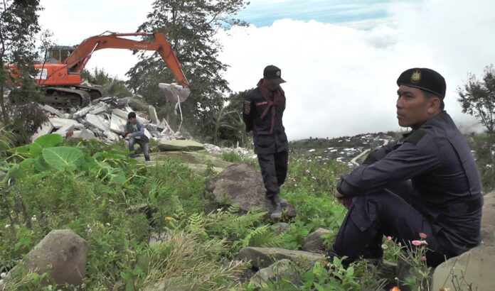 Interior department officers watch over the site where an illegally built structure is being demolished Thursday in Phetchabun province.