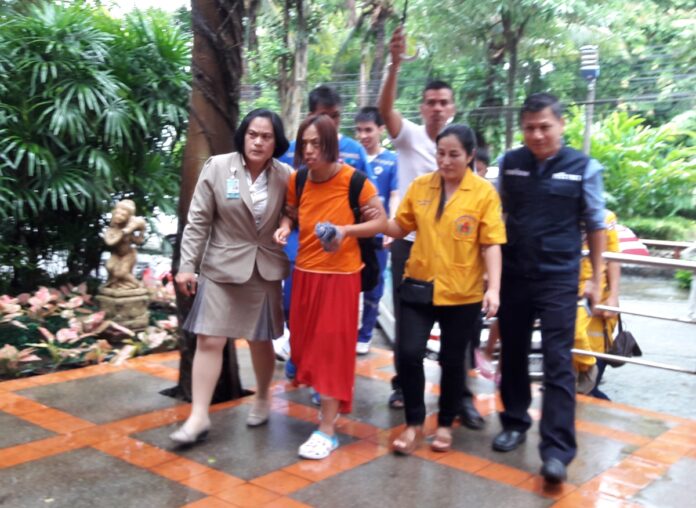 Gau Li Ping, in orange and red, is escorted to Phyathai Sriracha Hospital on Tuesday in Chonburi province.