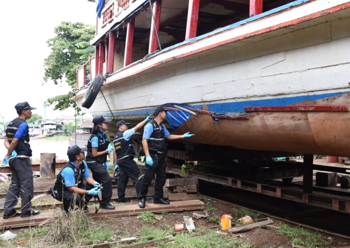 Police investigators on Wednesday inspect the boat salvaged from Chao Phraya River in Ayutthaya province.