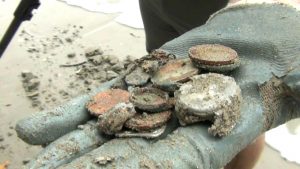 Stefan Burford shows off a fistful of coins he unearthed Thursday from Pak Meng Beach in Trang province.
