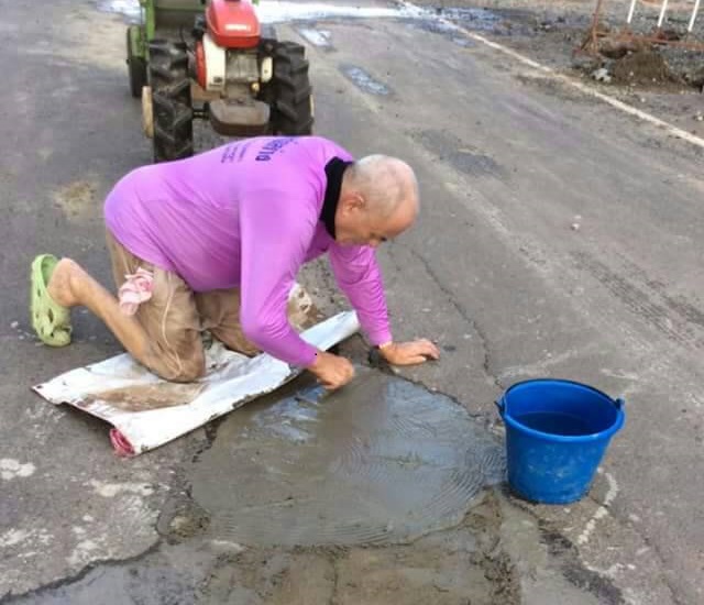 Peter Gowan, 76, fixes a Buriram road Sunday.