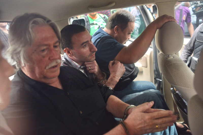 Two suspects identified as James Douglas Eger, at left, and Aaron Thomas Gabel, at middle, are taken Saturday from a police station to a Bangkok court.