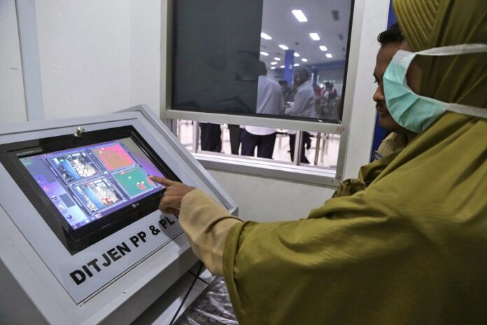 Indonesian Health Ministry officials operate a thermal scanner used to monitor ferry passengers arriving from Singapore at the arrival hall of Batam Center International Port in Batam, Indonesia on Thursday. Photo: M. Urip / Associated Press