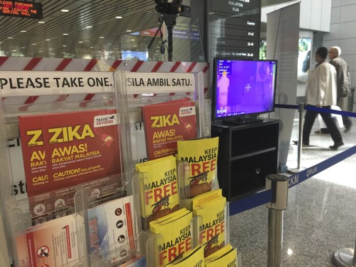 People walk past a travel advisory on the Zika virus infection Sunday in Kuala Lumpur International Airport. Photo: Vincent Thian / Associated Press