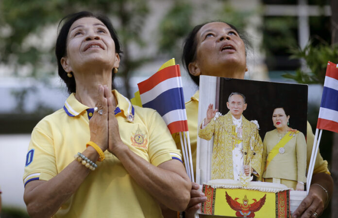Thais hold portraits of King Bhumibol Adulyadej and Queen Sirikit as they pray outside of the Grand Palace during the celebrations marking the 70th anniversary of his accession to the throne on June 9 in Bangkok. Photo: Sakchai Lalit / Associated Press