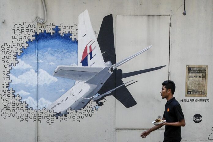 In this Tuesday, Feb. 23, 2016, file photo, a waiter walks past a mural of flight MH370 in Shah Alam outside Kuala Lumpur, Malaysia. Photo: Joshua Paul / Associated Press