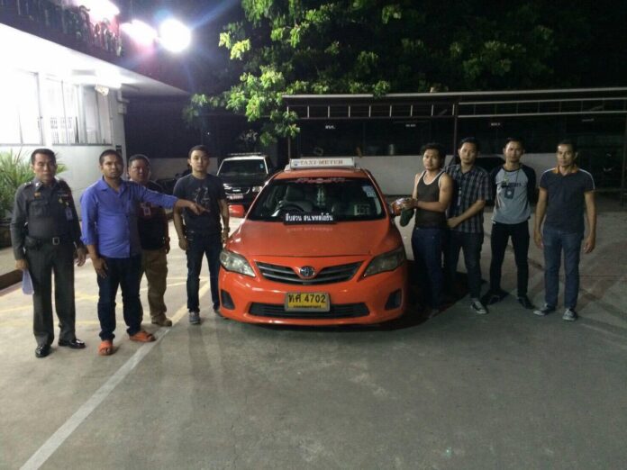 Yodchai Meepong, fourth from right, poses with police next to the taxi he is accused of stealing Saturday morning in Bangkok.