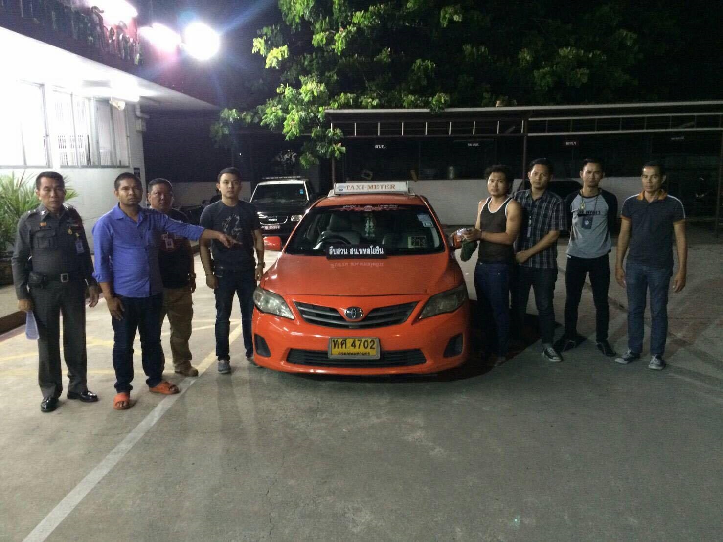 Yodchai Meepong, fourth from right, poses with police next to the taxi he is accused of stealing Saturday morning in Bangkok.