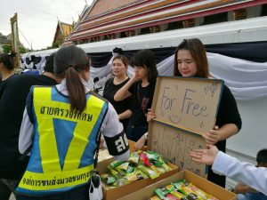 Volunteers give away snacks Thursday outside the Grand Palace.