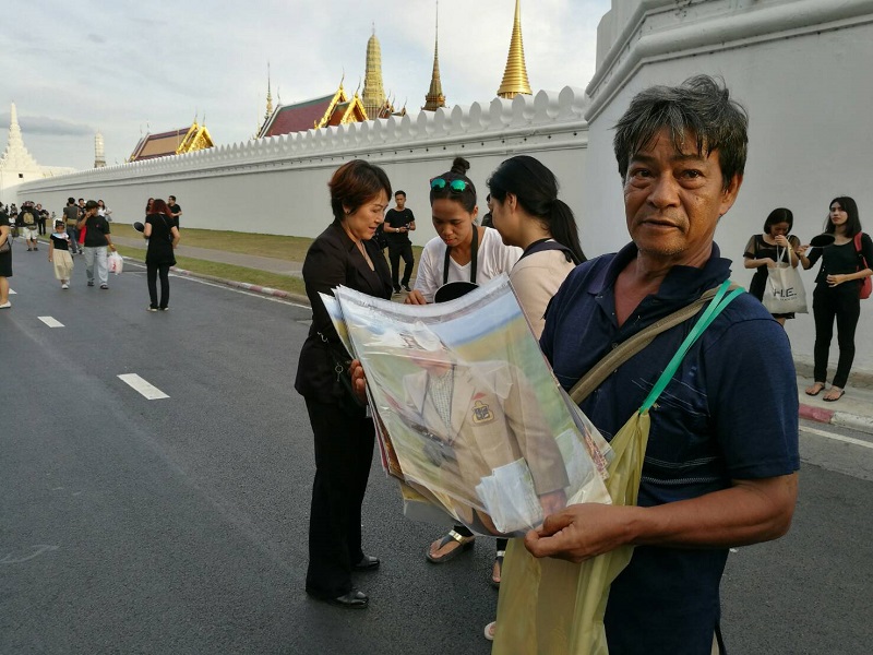 A man sells small posters of His Majesty the Late King for 40 baht each Thursday outside the Grand Palace in Bangkok.