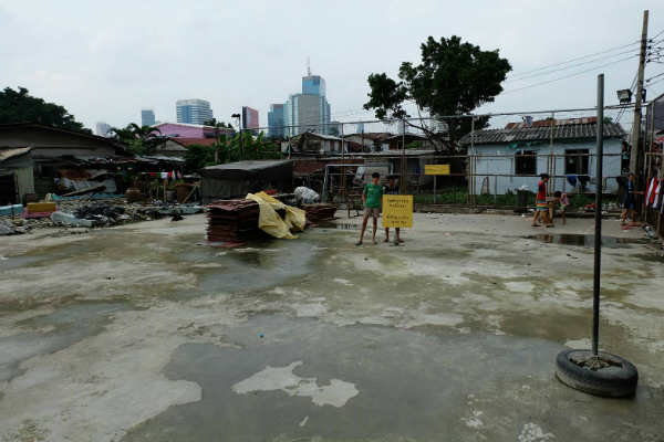 Pichit ‘Todd’ Cherngjorhor, 16, stands in front of a construction sign Thursday at an incomplete L-shaped soccer field in Bangkok's Khlong Toei district.