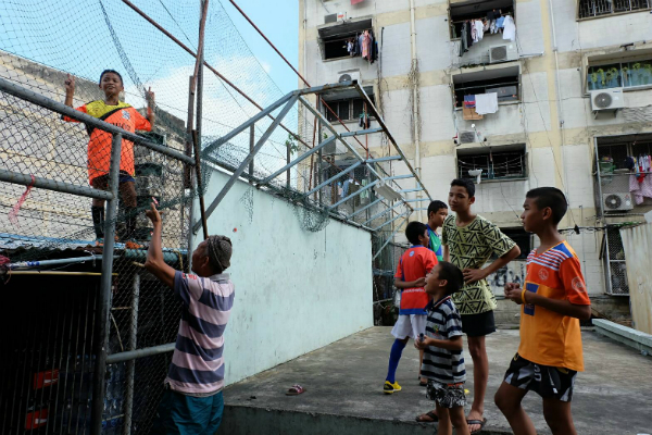 Phuwanat ‘Mike’ Piangtakoe, 12, strikes a pose as he climbs up to retrieve a ball.