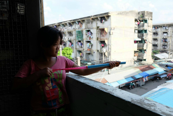 A girl shoots balls of clay from a PVC pipe Thursday in a stairwell in Bangkok’s Khlong Toei community.