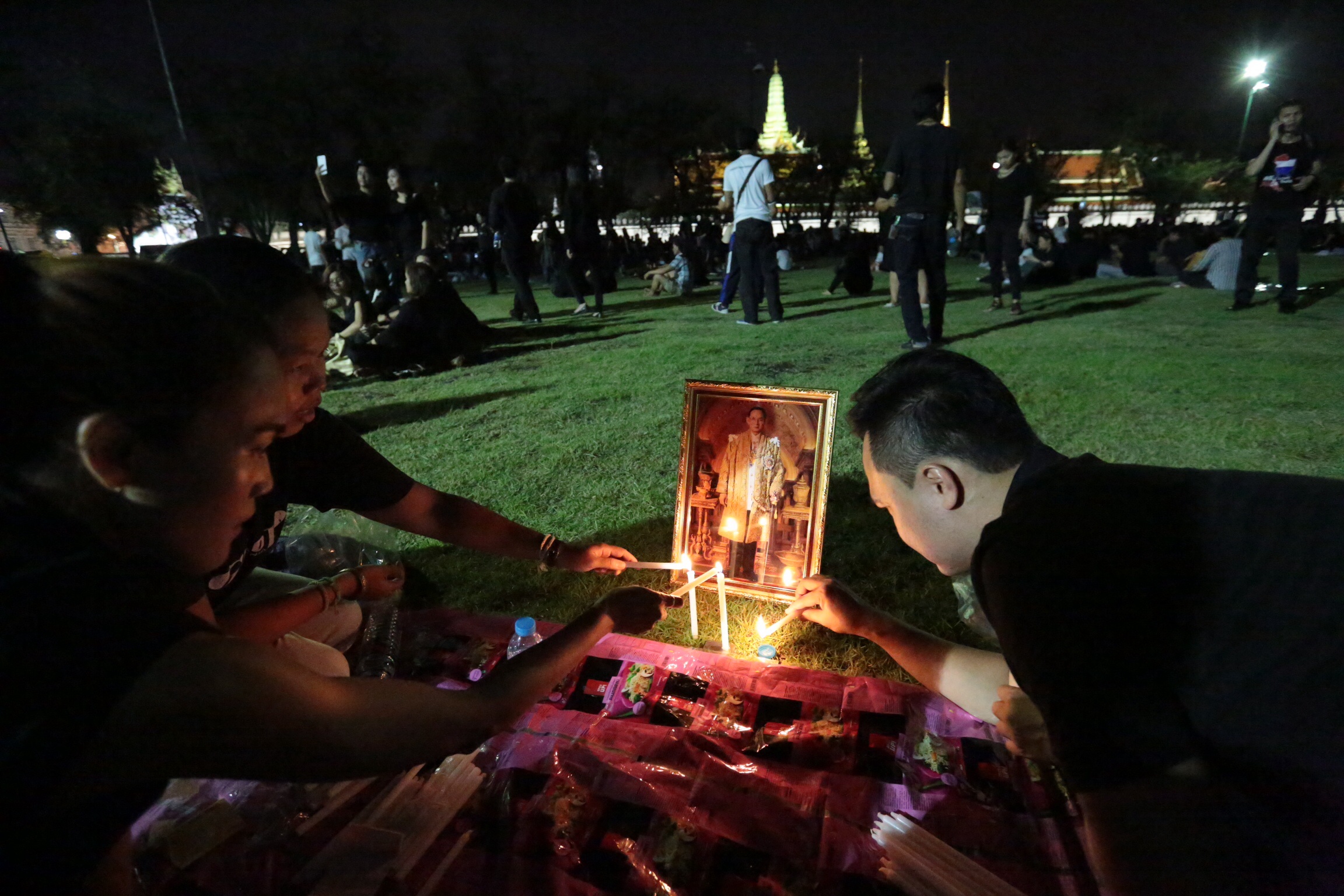Mourners light candles Saturday at the Sanam Luang in Bangkok.
