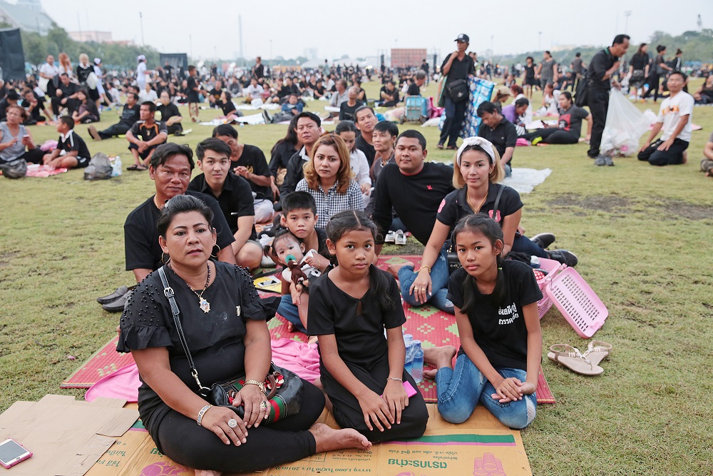 A family sits Tuesday in Bangkok’s Sanam Luang near the Grand Palace. 