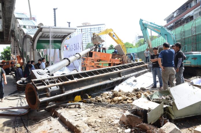 Workers remove a fallen crane from across the sidewalk at BTS Phra Khanong on Sukhumvit Road on Sunday in Bangkok.