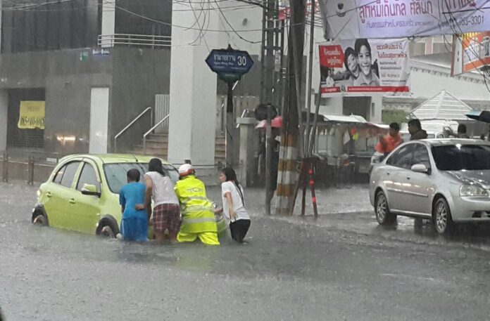 Policeman and motorists on Monday push a car that went kaput in the flood on Ngamwongwan Road.