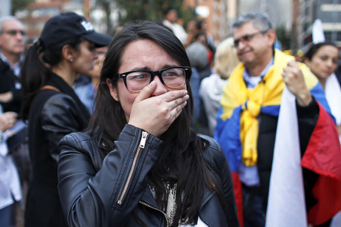 A supporter of the peace accord signed between the Colombian government and rebels of the Revolutionary Armed Forces of Colombia, FARC, cries Sunday as she follows on a giant screen the results of a referendum to decide whether to support the deal in Bogota, Colombia. Photo: Ariana Cubillos / Associated Press